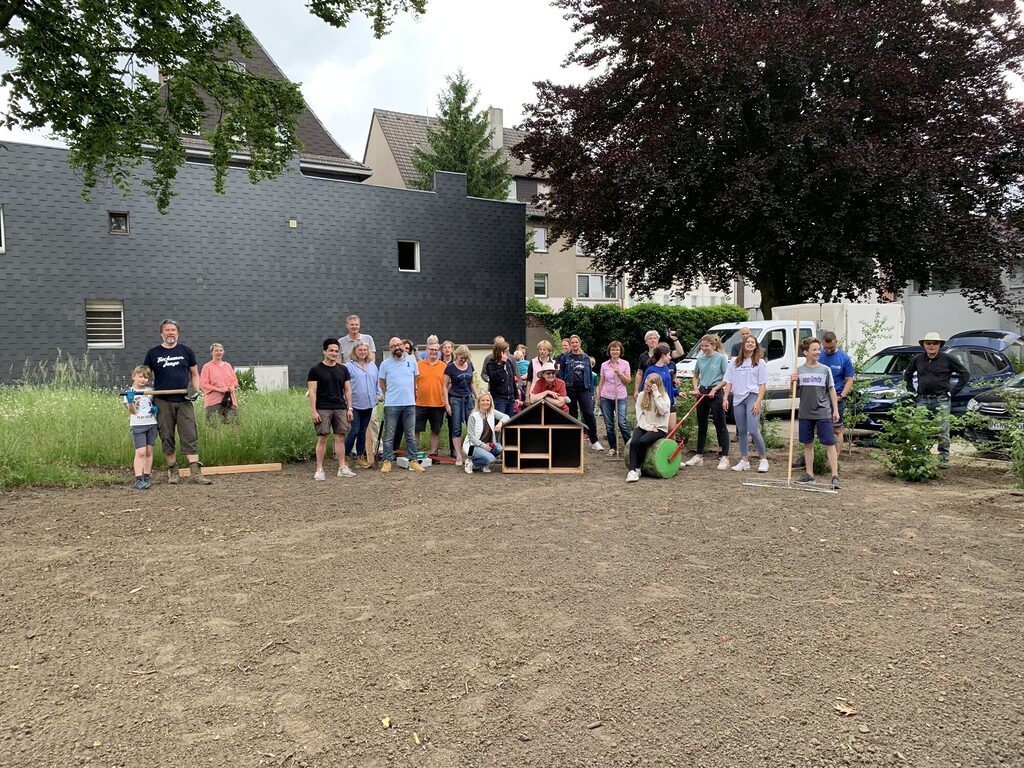 eine große Gruppe aus der rotarischen Familie in Bochum steht mit viel Werkzeug vor einer frisch bepflanzten Wiese