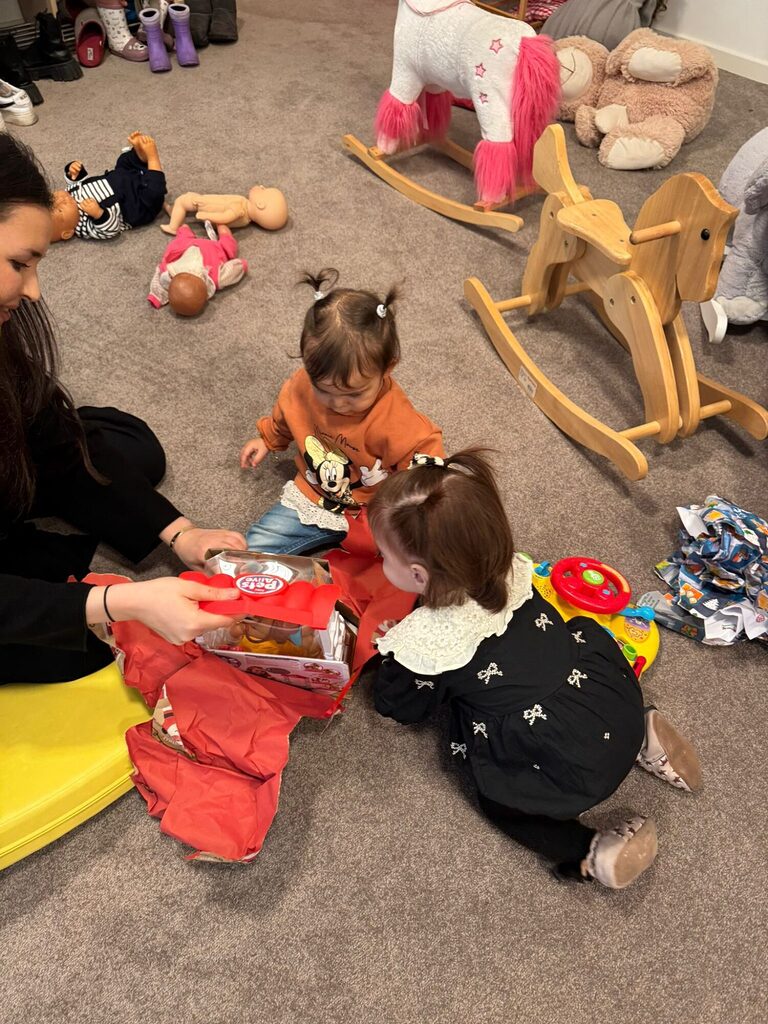 zwei Kleinkinder öffnen Geschenke, die sie durch die Herzenswunsch-Aktion bekommen haben