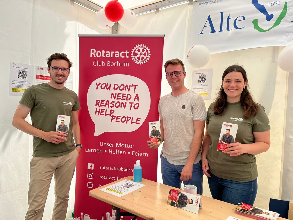drei Rotaracter posieren für ein Foto bei der DKMS-Aktion mit Spende-Sets und Stäbchen in der Hand.