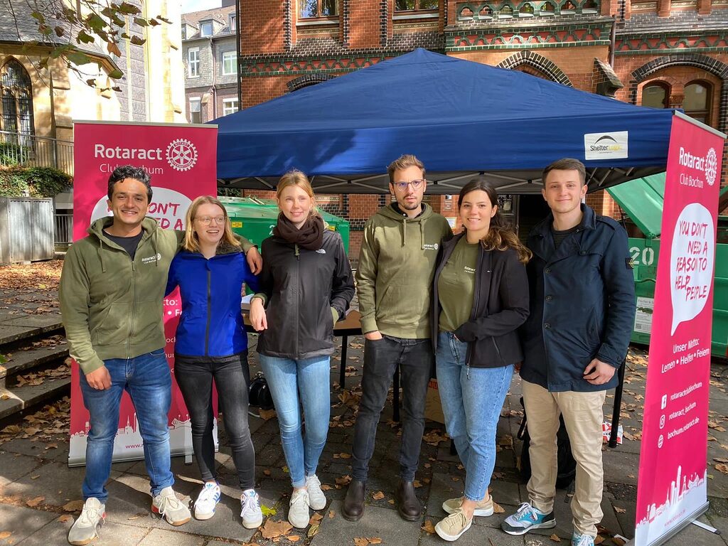 eine Gruppe Rotaracter steht für ein Gruppenfoto vor einem großen, grünen Container, in dem Altakten gegen Spenden entsorgt werden können